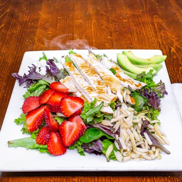 A Zio's Pizzeria salad with grilled chicken, strawberries, avocado, almonds, and feta cheese.