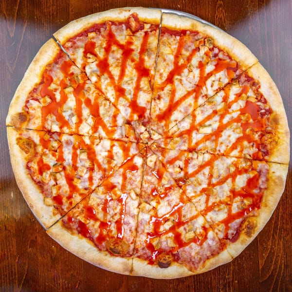 A Zio's Pizzeria buffalo chicken pizza, cut into slices, with hot sauce drizzled on top.